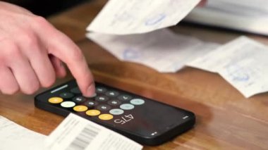 Summary and analysis of expenses and income for goods and services and salary. A person calculates utility bills and receipts using a smartphone calculator. A man counts money in cash dollars, euros.