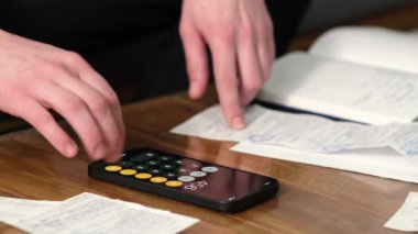 Adam hesap makinesi kullanır gelir ve giderleri hesaplar, krediyi öder, veri sonuçlarını laptop başvurusuna, belgelere, faturalara, faturalara, faturalara yazar, kapatır. Aile bütçesi kavramını yönet