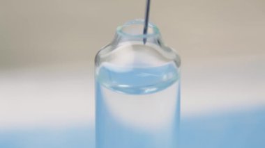 Bir kozmetolog ya da doktor enjeksiyon için bir şırınga hazırlar. Hafif arkaplanda enjeksiyon için iğne hazırlanıyor.