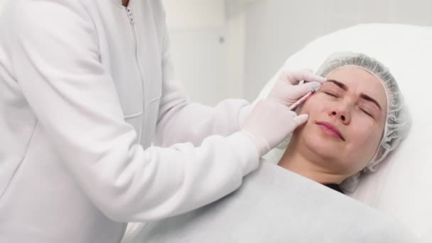 面部妇女在化妆品诊所得到美容注射 关闭美容师做肉毒杆菌注射在前额的病人在美容诊所 注射美容和医学概念 — 图库视频影像
