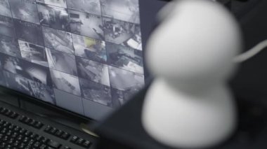 Male Officer Works on a Computer with Surveillance CCTV Video Footage in a Harbour Monitoring Center with Multiple Cameras on a Big Digital Screen. Employees Sit in Front of Displays with Big Data.