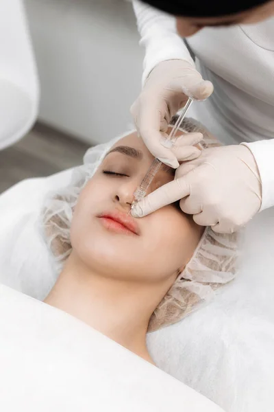 close-up, female lips. Surgeon, in medical gloves, carefully and slowly injects hyaluronic acid into woman\'s lips with a syringe. lip augmentation procedure. beauty injections. Plastic surgery.