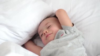 Huzurlu bebek odadaki yatakta uyuyor. Yumuşak odaklanma. Uyuyan bebek konsepti. Çocuk evde uyuyor..