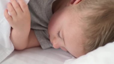 Huzurlu bebek odadaki yatakta uyuyor. Yumuşak odaklanma. Uyuyan bebek konsepti. Çocuk evde uyuyor..