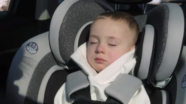 可爱的小孩2 3岁睡在一个现代化的汽车座位上 路上的儿童安全 安全的旅行方式 用安全带系在车上 带着幼儿的概念 — 图库视频影像