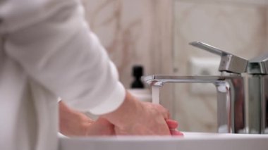 Beyaz tenli bir insan yazın ellerini suyla yıkar, cilt hijyeni ve koronavirüsten korur, parmaklarını yıkar, bakterilerin yayılmasını engeller, su sıçratır ve sinek düşer.