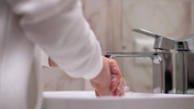 Beyaz tenli bir insan yazın ellerini suyla yıkar, cilt hijyeni ve koronavirüsten korur, parmaklarını yıkar, bakterilerin yayılmasını engeller, su sıçratır ve sinek düşer.