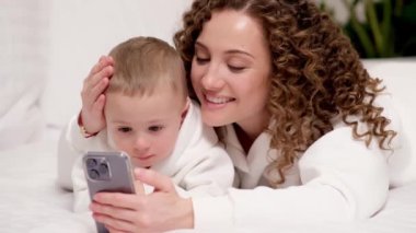 Anne ve 2 yaşındaki küçük oğlu yatağa uzanmış, cep telefonuna bakıyor, gülüyor, çizgi film izliyor, video görüşmeleri yapıyor, internette eğleniyorlar. İki nesildir aile yeni uygulama kullanıyor