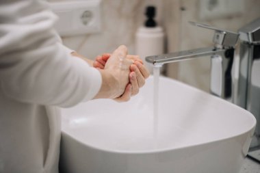 Adam suyu açıyor, ellerini köpürüyor ve ellerini güvenli bir şekilde yıkıyor. Odalarda büyük ve temiz bir banyo vardı. Dışarı çıktıktan sonra ellerini yıka.