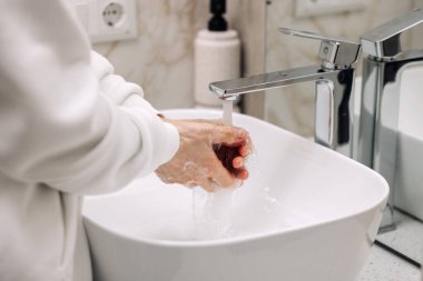 Adam suyu açıyor, ellerini köpürüyor ve ellerini güvenli bir şekilde yıkıyor. Odalarda büyük ve temiz bir banyo vardı. Dışarı çıktıktan sonra ellerini yıka.