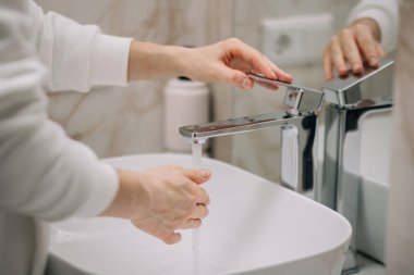 Adam suyu açıyor, ellerini köpürüyor ve ellerini güvenli bir şekilde yıkıyor. Odalarda büyük ve temiz bir banyo vardı. Dışarı çıktıktan sonra ellerini yıka.