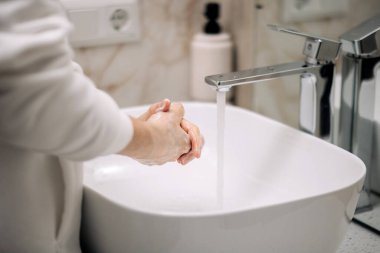 Beyaz tenli bir adam yazın ellerini suyla yıkar. Cilt hijyeni ve koronavirüsten korur. Parmaklarını yıkar, bakterilerin yayılmasını engeller.