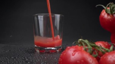 bir demet domates ve içine domates suyu dökülen bir bardak siyah arka plan. Domates, yıkanmış ve meyve suyuna hazır.