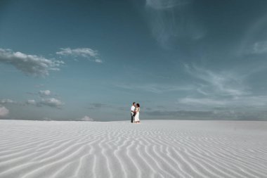 Genç çift kum tepelerinde yürürken eğleniyor. Sahra çölünde yürüyen romantik bir gezgin. Macera yolculuğu yaşam tarzı konsepti. (seçici odaklanma)