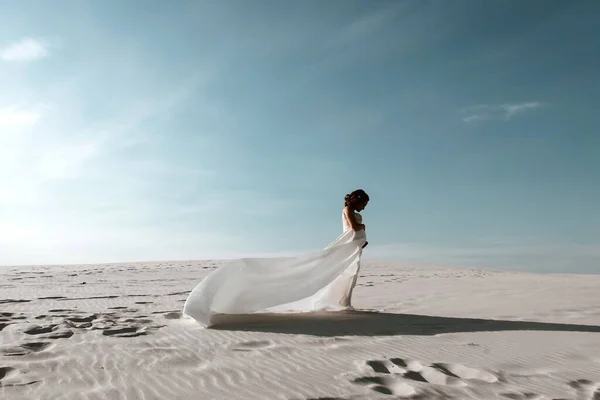 Beautiful Young Pregnant Women, 8 months Pregnant, wearing white lace dress standing in desert sand dune scene