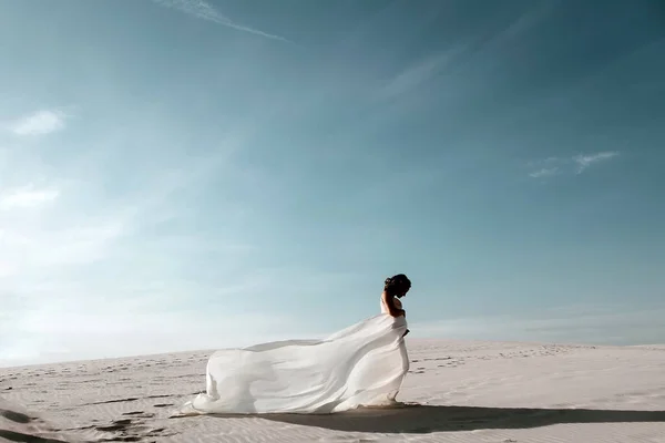 Beautiful Young Pregnant Women, 8 months Pregnant, wearing white lace dress standing in desert sand dune scene