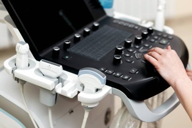 Doktorun eli, ultrason tarayıcısı kullanarak hastanın tıbbi muayenesini yapıyor. Ultrason makinesinin yakın çekimi ve üzerinde çalışan bir doktor eli. Kavram