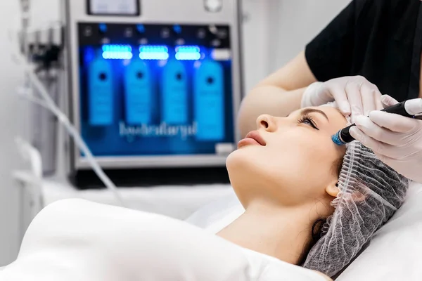 Kozmetoloji kliniğindeki güzel kadın hastalara hidro soyma işlemi yapan tıbbi eldivenler giyen profesyonel bir dermatolog. Yüz tedavisini kapat.