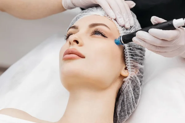 stock image Professional dermatologist in medical gloves doing hydro peeling procedure for beautiful woman patient in cosmetology clinic. Close up facial treatment.