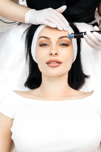 Cosmetologist doing hydrafacial treatment on woman face in beauty clinic