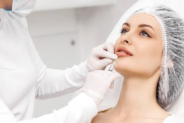 Kesilmiş şehvetli kadın dudakları, prosedür dudak büyütme. Kadınların ağzına yakın şırınga, dudaklarının şekli için iğne.