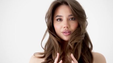 Genç kadın beyaz arka planda gözlerini aç. Stüdyoda kameraya bakan gülümseyen kıza yaklaş. Kıvırcık saçlı manken yüzü gülümsüyor. Neşeli kızın portresi, açık gözler. Kadın doğası güzelliği