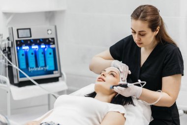 Hidrolik güzellik prosedürü, temiz yüz, temiz deri. Kozmetoloji kliniğinde kadın hasta, kozmetoloji kliniğinde doktor güzellik prosedürü uyguluyor, güzellik uzmanı hastanın yüzünü temizliyor.