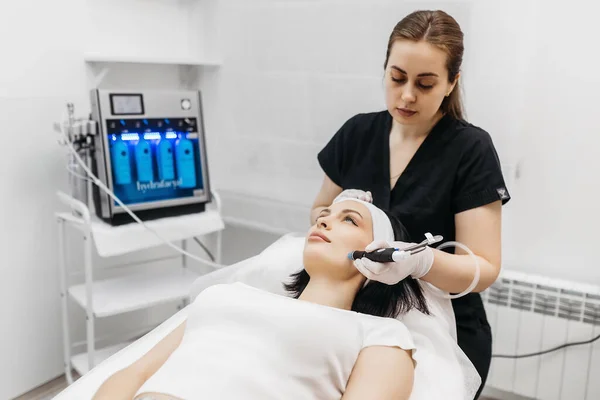 Hydropeeling beauty procedure, cleaning face, Clean Skin. Woman patient in cosmetology clinic, doctor performing beauty procedure in cosmetology clinic, beautician cleaning patient's face