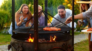 Çoklu etnik çeşitliliğe sahip bir grup insan eğleniyor, birbirleriyle sosyalleşiyor ve açık hava yemeğinde barbekü yapıyorlar. Sıcak bir yaz gününde aile ve arkadaşlar evlerinin önünde toplandılar..