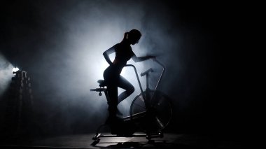 Genç bir kadın karanlık spor salonunda egzersiz yapıyor..