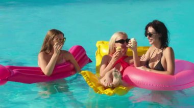 Bir grup güzel genç kadın, güneşli bir yaz gününde dondurma yiyor ve havuzda eğleniyorlar. Rahatlama, dinlenme ve keyif kavramı