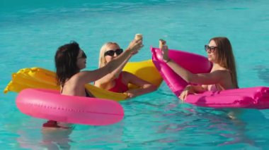 Bir grup güzel genç kadın, güneşli bir yaz gününde dondurma yiyor ve havuzda eğleniyorlar. Rahatlama, dinlenme ve keyif kavramı