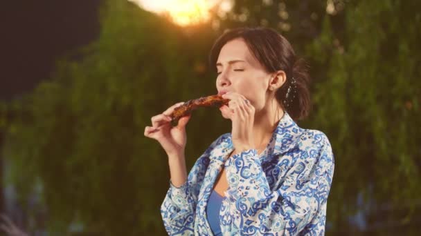 Jovem Mulher Comendo Carne Grelhada Quintal Desfrutando Churrasco Dia Ensolarado — Vídeo de Stock