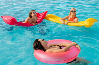 Bir grup güzel, genç kadın çilekli dondurma yiyor ve havuzda eğleniyorlar..