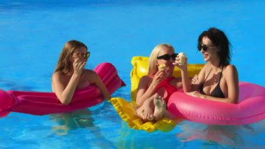 Bir grup güzel genç kadın, güneşli bir yaz gününde dondurma yiyor ve havuzda eğleniyorlar. Rahatlama, dinlenme ve keyif kavramı