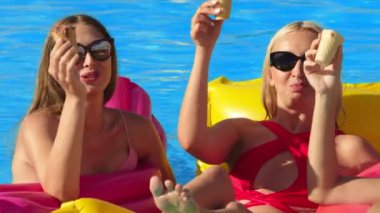 Bir grup güzel genç kadın, güneşli bir yaz gününde dondurma yiyor ve havuzda eğleniyorlar. Rahatlama, dinlenme ve keyif kavramı