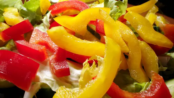 Red, Orange, Yellow, and Green Bell Peppers Cut into Thin Strips: Bell peppers cut in batonnets on a bamboo cutting board with a chef\'s knife.