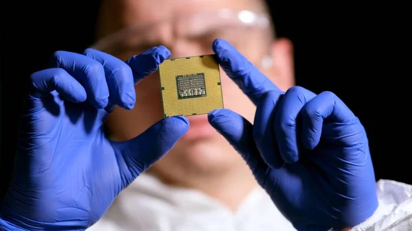 stock image Engineer man in sterile suit is holding Microchip with symbols in modern design factory , futuristic and artificial intelligence concept