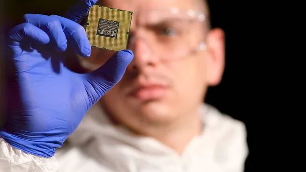 Steril takım elbiseli mühendis modern tasarım fabrikasında sembollü mikroçip tutuyor. Fütürist ve yapay zeka kavramı.