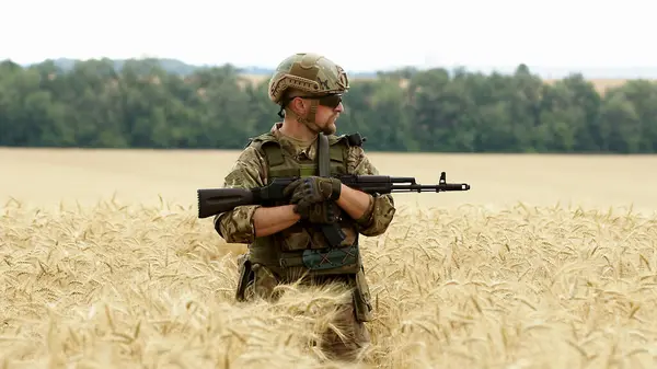 Soldier man, machine gun and outdoor with aim, field and nature for war, fight and army in countryside. Military service, battlefield and agent with weapon, gear and helmet for conflict in Ukraine.