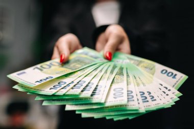 Şık takım elbiseli genç bayan iş kadını elinde iyi miktarda avroyla şık giyinmiş. İş ve gelir kavramı