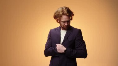 İş elbisesi giymiş yakışıklı, sakalsız genç bir adam. Stüdyoda sarı bir arka planda izole edilmiş. İnsanlar samimi duygular, yaşam tarzı konsepti.