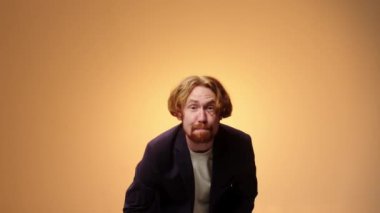 İş elbisesi giymiş yakışıklı, sakalsız genç bir adam. Stüdyoda sarı bir arka planda izole edilmiş. İnsanlar samimi duygular, yaşam tarzı konsepti.