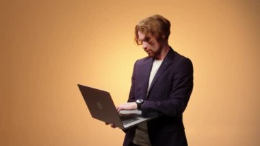 Dizüstü bilgisayarı olan karizmatik iş adamı daktilo ediyor ve parmak gösteriyor. Çevrimiçi iş kavramı