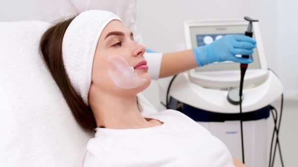 化粧品学者は バイオリバイタライゼーション手順の後に患者の顔の皮膚にクリームマスクを塗布しています 美容クリニックの女性 — ストック動画