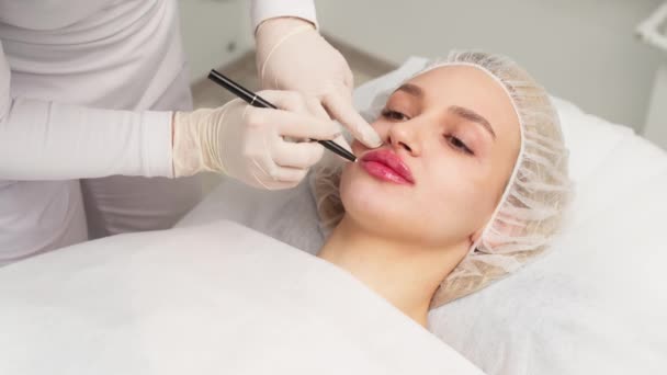 Kosmetologen Gör Markeringar Patientens Ansikte Ritar Korrigeringslinjer Före Ansiktets Konturförfarande — Stockvideo