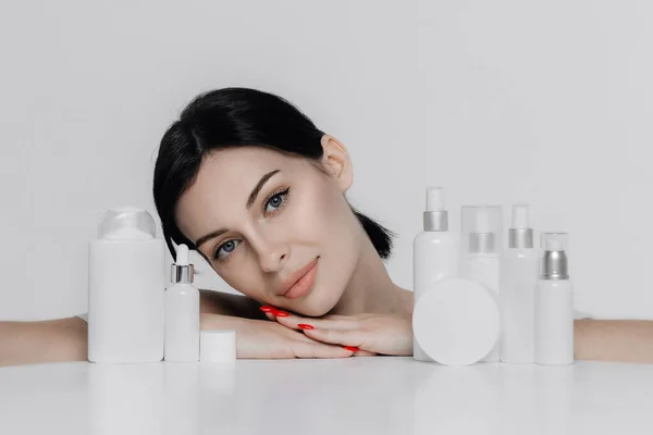 Woman showing cosmetic products branding mockup. Daily skincare and body care routine. Natural cosmetic cream, serum, white bottles packaging, bio organic product.