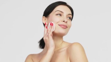 Beyaz arka planda izole edilmiş pamukla yüzünü temizleyen genç ve çekici bir kadının portresi. Mükemmel Taze Cilt. Saf Güzellik Modeli. Özen Konsepti.