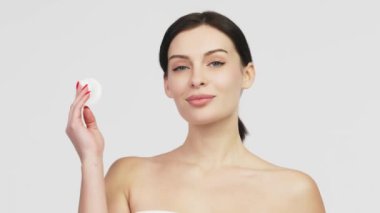 Beyaz arka planda izole edilmiş pamukla yüzünü temizleyen genç ve çekici bir kadının portresi. Mükemmel Taze Cilt. Saf Güzellik Modeli. Özen Konsepti.