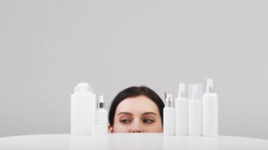 Mükemmel sağlıklı cilde sahip güzel beyaz bir kadın bir ürün teklif ediyor. Beyaz etiketli kozmetik şişeler. Güzellik blogu, kuaför konsepti, minimalizm marka paketleme modeli